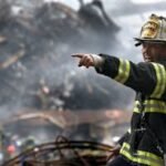 A firefighter in action at a disaster scene, directing rescue operations amidst smoke and debris.