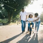 Happy family teaching their child to cycle on a sunny day outdoors.